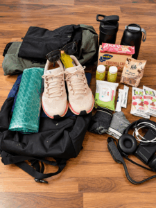 Rucksack mit Laufschuhen, Sportkleidung, Trinkflaschen, Snacks und weiterer Ausrüstung für Bewegung und längere Touren.